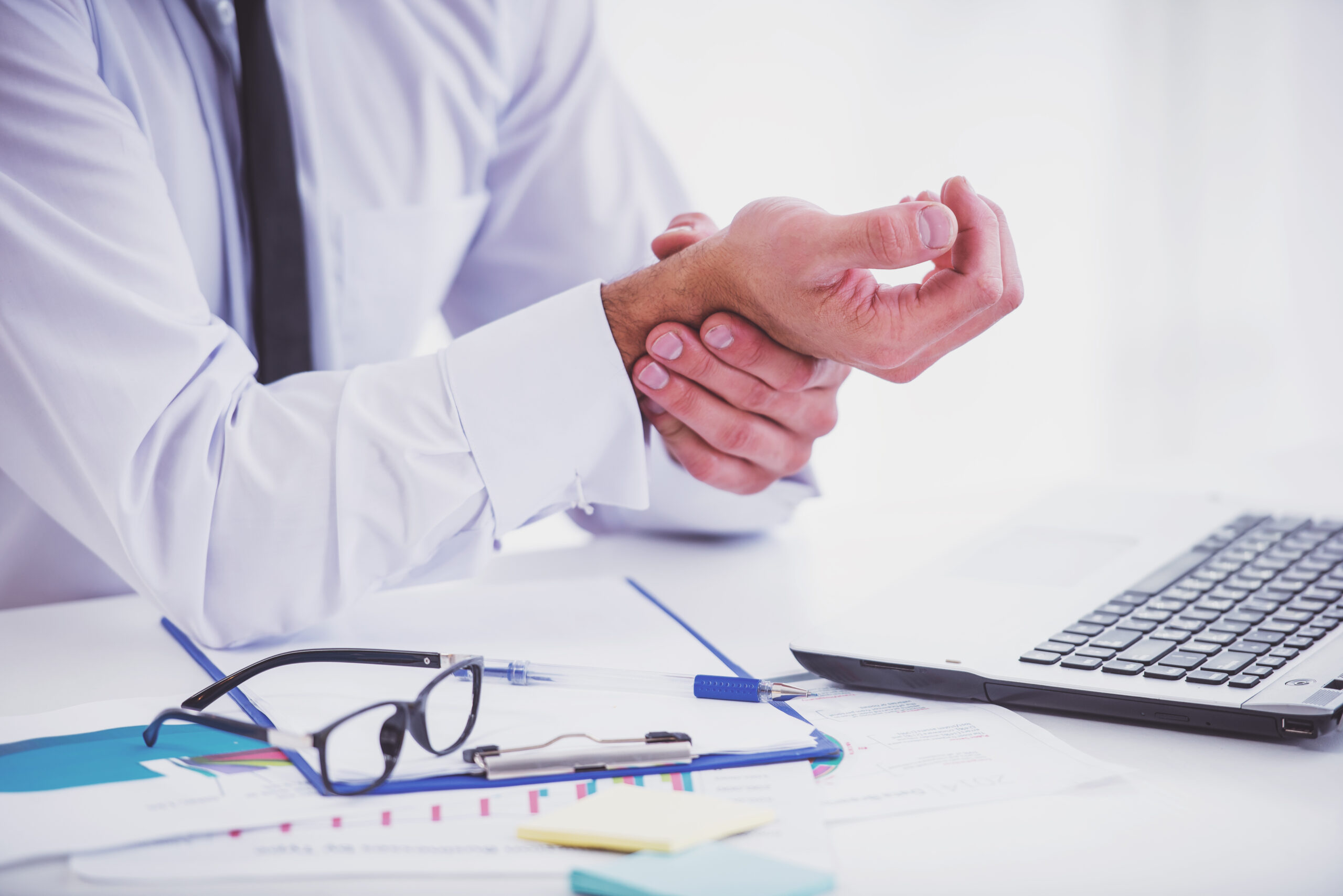 Illness hand. Portrait of a businessman while working in his office, holding hand