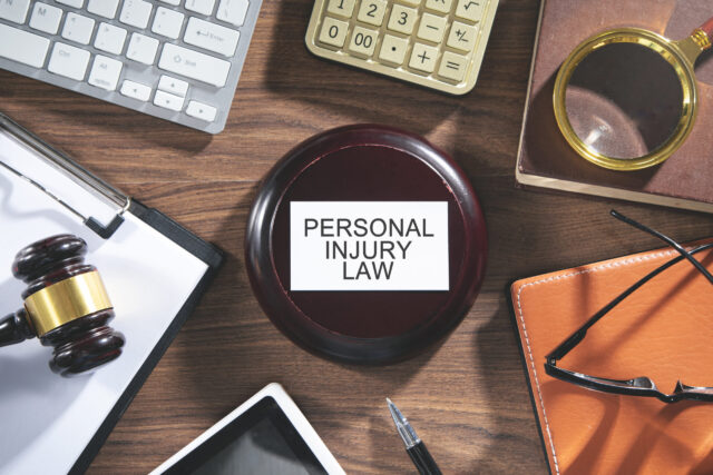 A wooden desk with a gavel, glasses, a magnifying glass, a calculator, a tablet, a keyboard, and a clipboard is arranged neatly in an office setting. A nameplate reads 