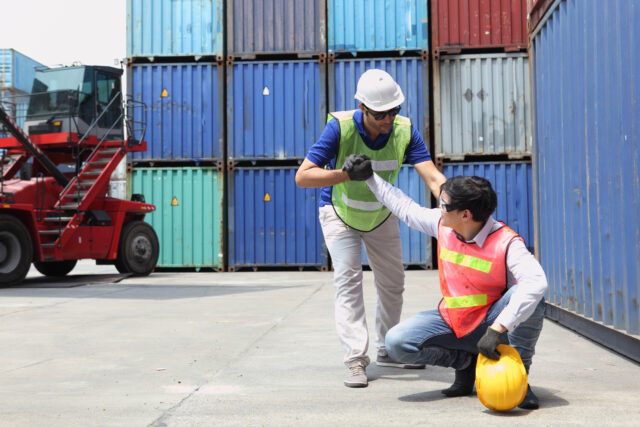 Construction worker or Industrial Engineers has an accident while working on Container ship in import and export business logistic company. Industry and Transportation concept.